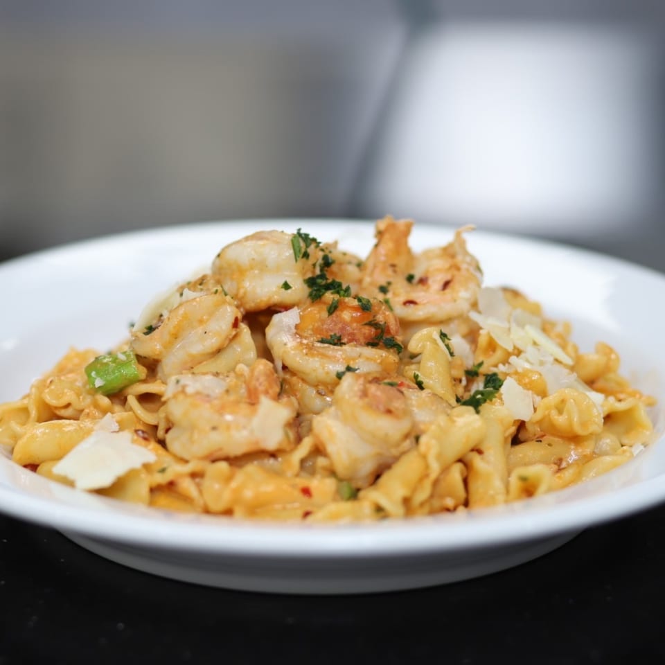 Pasta To Go's creamy shrimp pasta with penne, parmesan, and parsley in a white bowl.